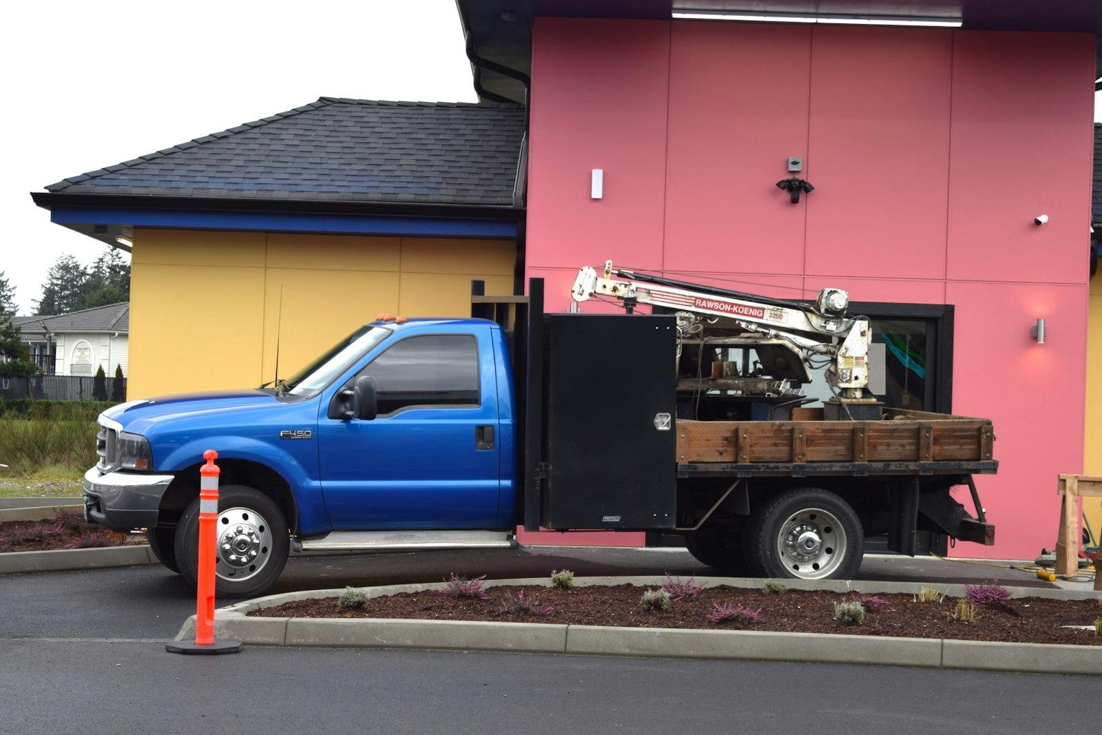 A blue truck parked in front of a pink building