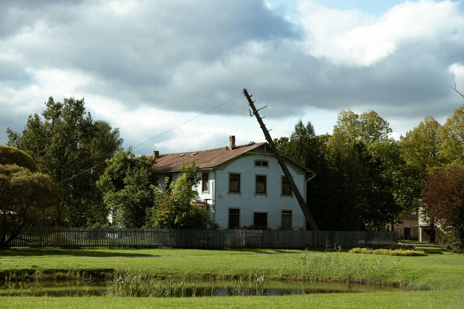 Old house with a tilted windmill and trees.