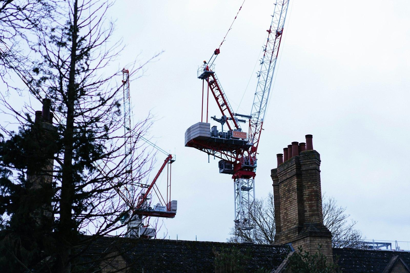 Construction cranes rise above rooftops and bare trees.
